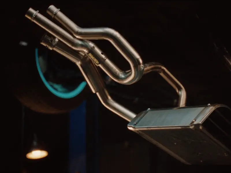 Polished exhaust pipework and muffler under a raised car