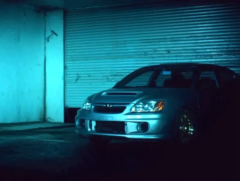 Silver sedan parked at a workshop roller door at night
