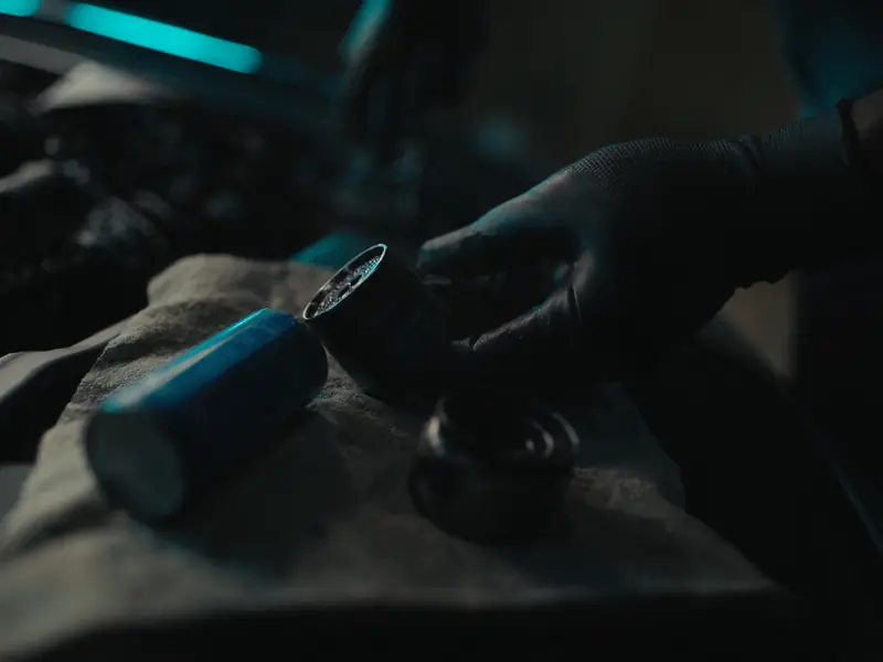 Gloved hands with a new oil filter on a workshop rag