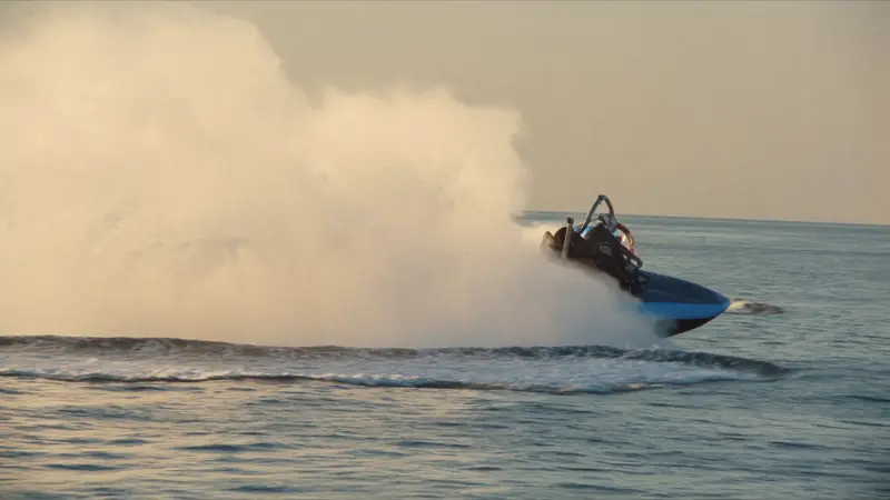 Jet ski carving a hard turn with a big wall of spray at golden hour
