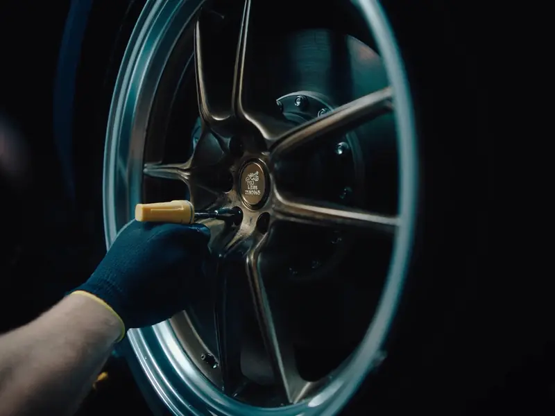 Gloved hand tightening a wheel nut on a bronze alloy wheel
